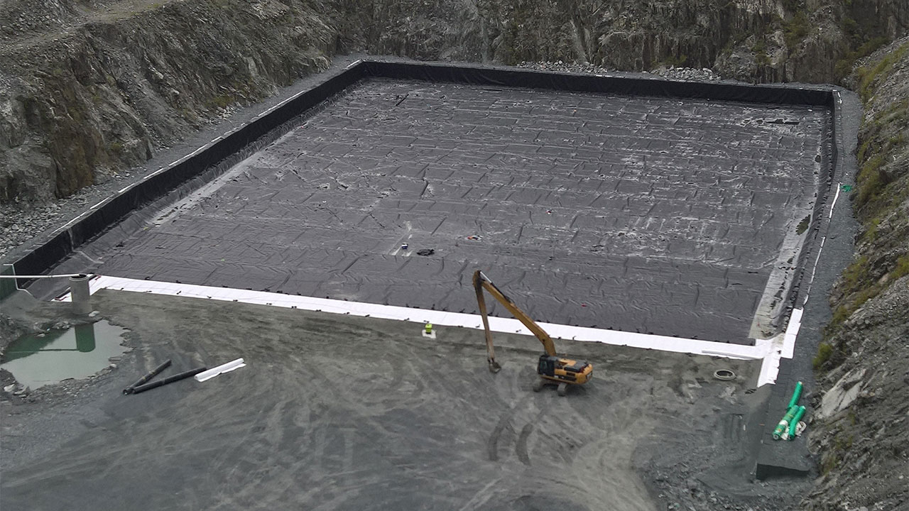 A construction site showing a large pit with a crane