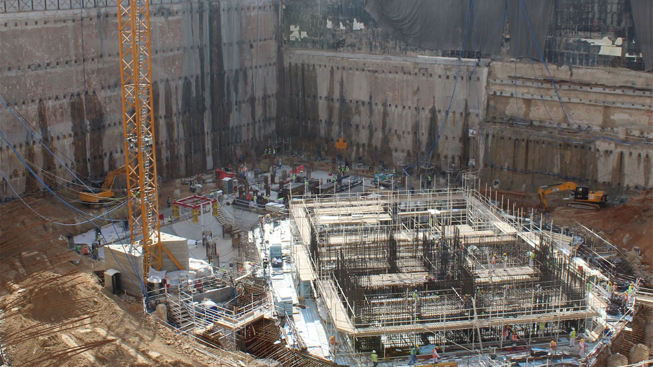 A construction site busy with activity, showcasing a tall tower and multiple workers involved in building operations